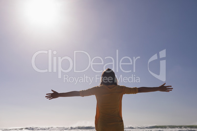 Woman standing with arms outstretched at beach