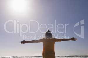 Woman standing with arms outstretched at beach