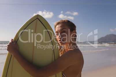 Female surfer standing with surfboard at beach