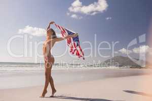Young woman holding waving American flag at beach