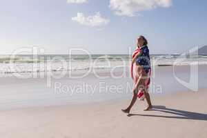 Young woman wrapped in American flag at beach