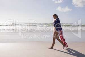Young woman wrapped in American flag at beach
