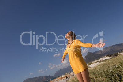 Woman standing with arms outstretched on the beach