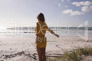 Young woman standing with arms outstretched on the beach