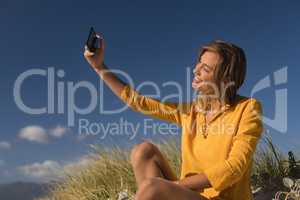 Woman taking selfie with mobile phone at beach