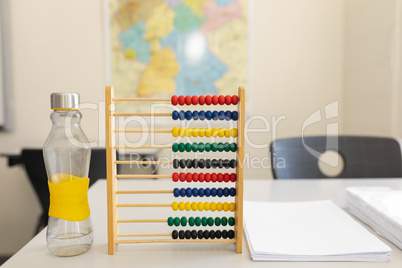 Water bottle, abacus and bunch of paper on the desk in school