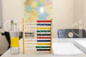 Water bottle, abacus and bunch of paper on the desk in school