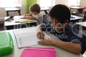 Schoolboy studying in classroom sitting at desks in school