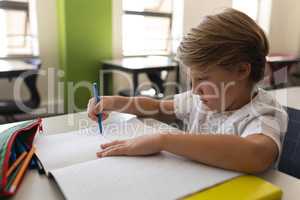 Schoolboy studying in classroom sitting at desks in school