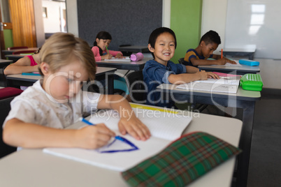 Schoolboy looking at camera while studying in classroom