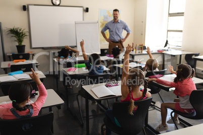 School kids raising hand in classroom