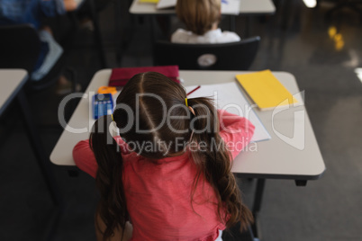 Schoolgirl studying in classroom sitting at desks in school