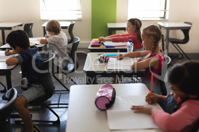 Kids studying in classroom sitting at desks in school