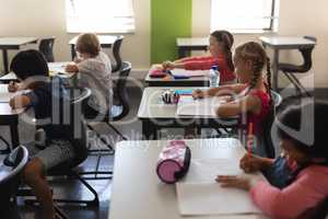 Kids studying in classroom sitting at desks in school