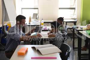 Young school teacher helping boy with study in classroom