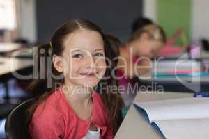 Schoolgirl looking at camera while sitting in classroom