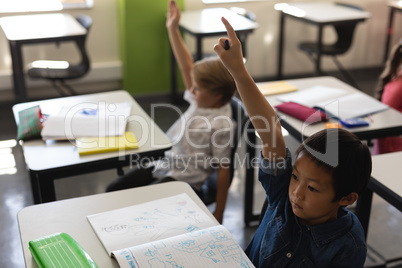 Schoolboy raising hand in classroom