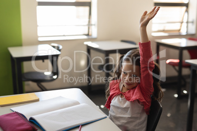 Schoolgirl raising hand in classroom