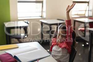 Schoolgirl raising hand in classroom