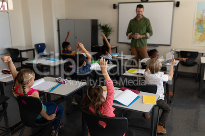 School kids raising hand in classroom of elementary school