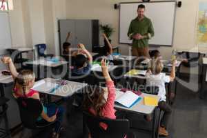 School kids raising hand in classroom of elementary school