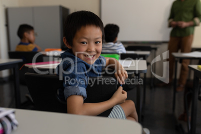 Happy schoolboy looking back in classroom