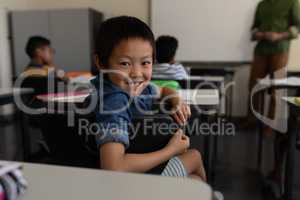 Happy schoolboy looking back in classroom