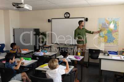 Teacher pointing at a map in classroom