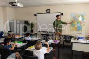 Teacher pointing at a map in classroom