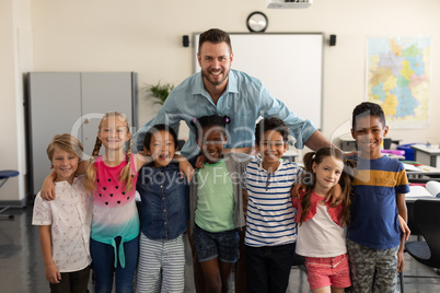 Happy school kids and teacher standing classroom