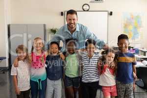 Happy school kids and teacher standing classroom