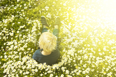 Blonde Child Sitting In A Daisy Flower Meadow