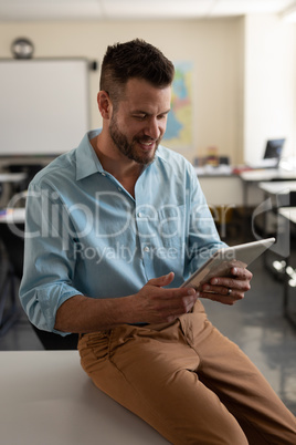 Male teacher using digital tablet in classroom