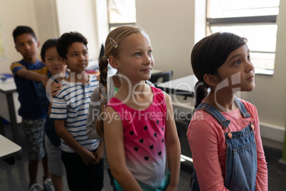 School kids standing in row in classroom of elementary school
