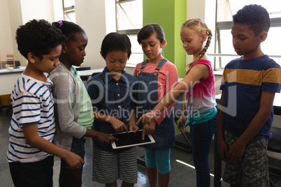 Group of school kids studying together on digital tablet in classroom