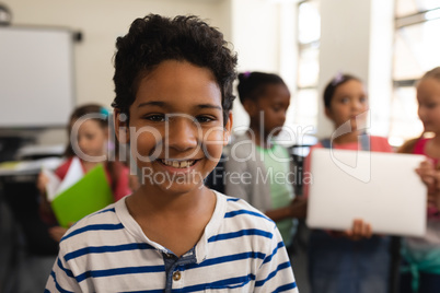 Happy schoolboy looking at camera in classroom of elementary school