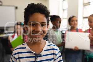Happy schoolboy looking at camera in classroom of elementary school