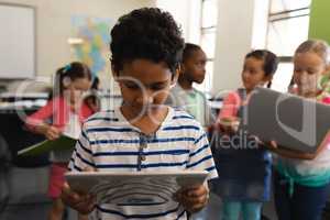 Schoolboy studying on digital tablet in classroom