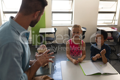 School kids smiling while teacher teaching in classroom
