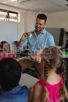 Male teacher explaining anatomical model in classroom