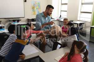 Male teacher teaching his kids about geography by using globe in classroom