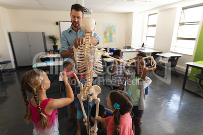 Male teacher explaining skeleton model in classroom