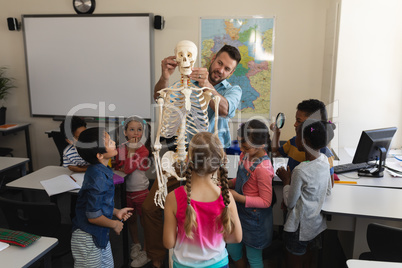 Male teacher explaining skeleton model in classroom