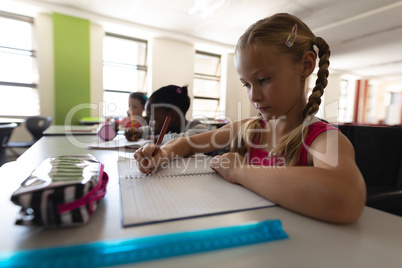 Side view of schoolgirl studying at desk in classroom