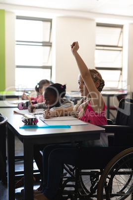 Disable schoolgirl raising hand in classroom of elementary school
