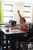 Disable schoolgirl raising hand in classroom of elementary school