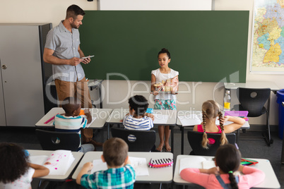 High angle view of schoolgirl explaining anatomical model in classroom