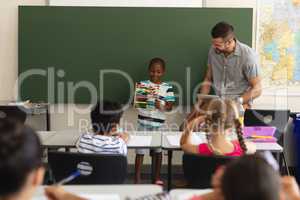 Front view of black schoolboy using maths abacus in classroom