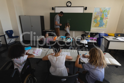 Rear view of schoolkids studying in classroom