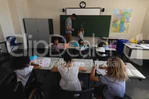 Rear view of schoolkids studying in classroom
